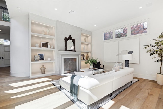 living room featuring light wood-type flooring and built in shelves