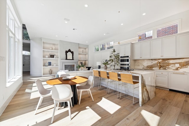 kitchen with a center island, a breakfast bar area, white cabinets, and light hardwood / wood-style floors