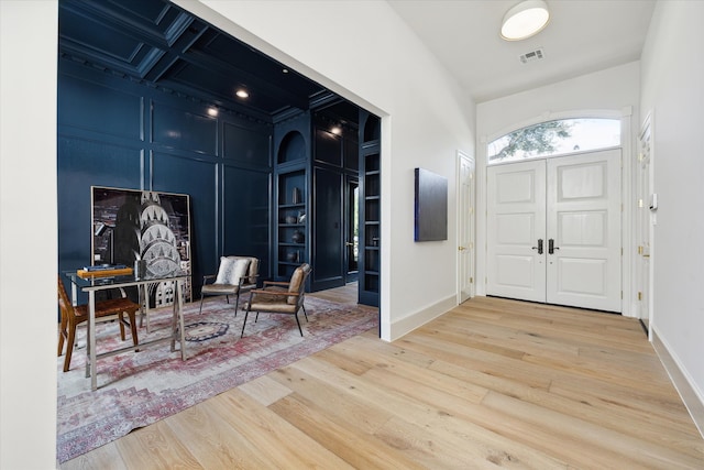 foyer entrance with coffered ceiling and light wood-type flooring