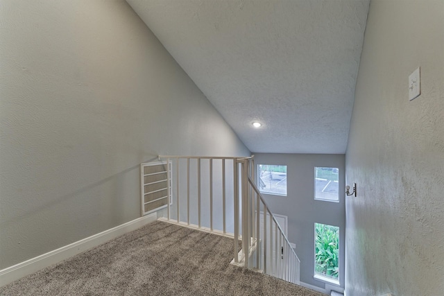 stairway featuring carpet flooring, lofted ceiling, and a textured ceiling