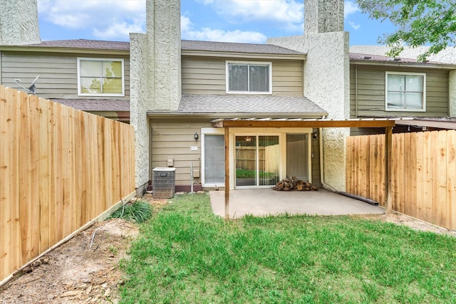 back of property with central AC unit, a patio area, and a yard