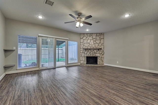 unfurnished living room featuring a fireplace, a textured ceiling, ceiling fan, and dark wood-type flooring