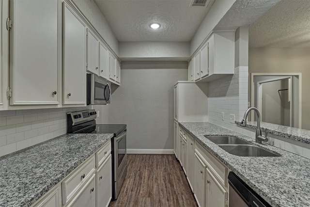 kitchen with light stone countertops, sink, a textured ceiling, white cabinets, and appliances with stainless steel finishes