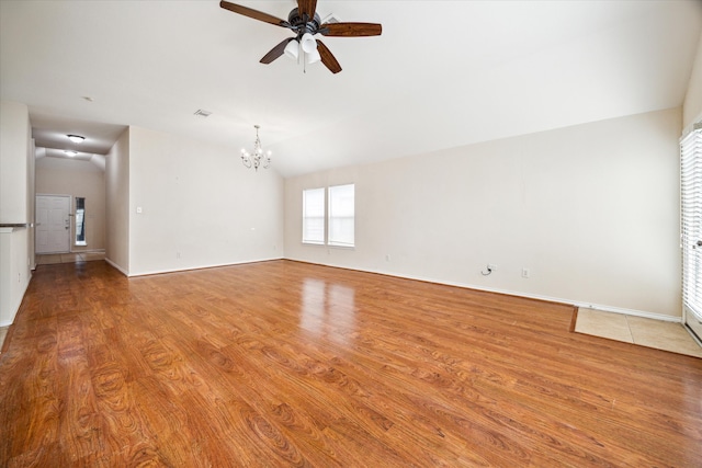 unfurnished living room with ceiling fan with notable chandelier, wood-type flooring, and vaulted ceiling