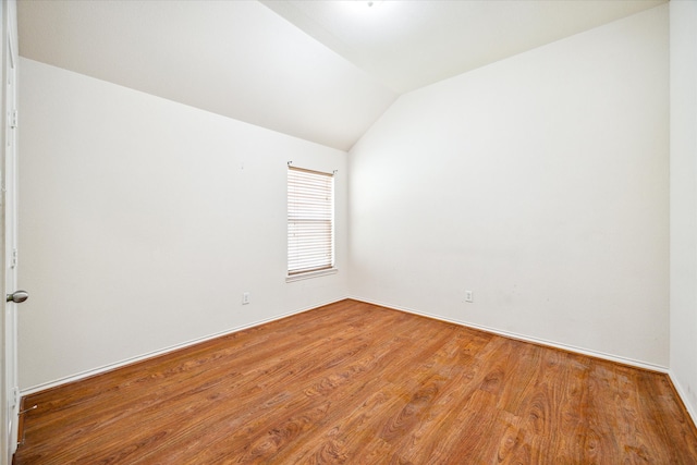 empty room featuring wood-type flooring and vaulted ceiling