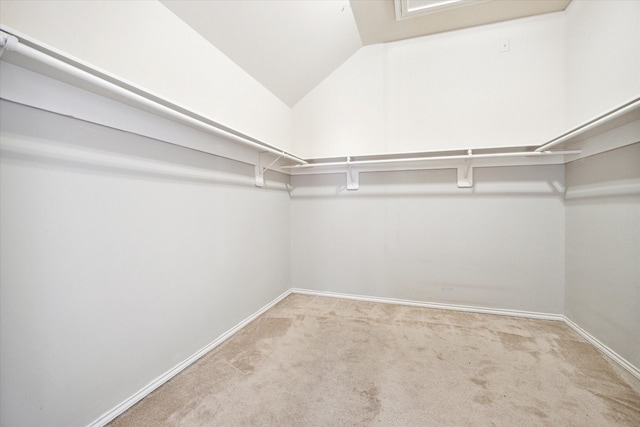 walk in closet with light carpet and vaulted ceiling