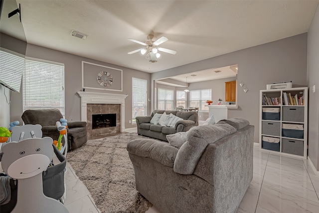 living room with ceiling fan and a tile fireplace