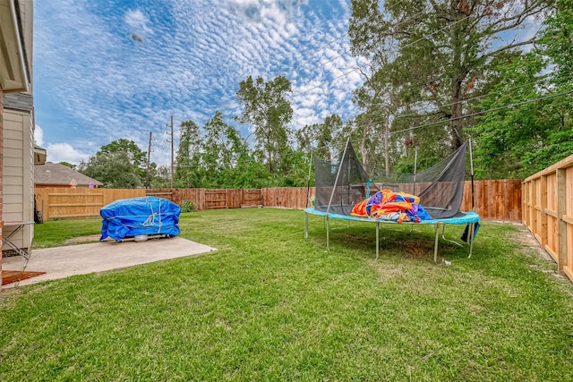 view of yard featuring a trampoline and a patio