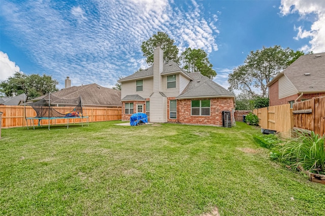 back of property with a trampoline and a lawn