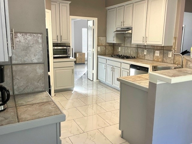 kitchen with tasteful backsplash, sink, kitchen peninsula, stainless steel appliances, and white cabinets