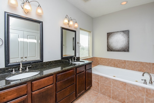 bathroom featuring vanity, tile patterned flooring, and tiled bath