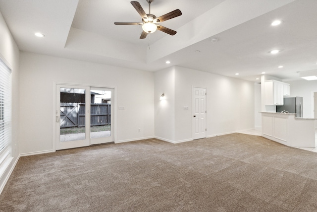 unfurnished living room with ceiling fan, a healthy amount of sunlight, and light colored carpet