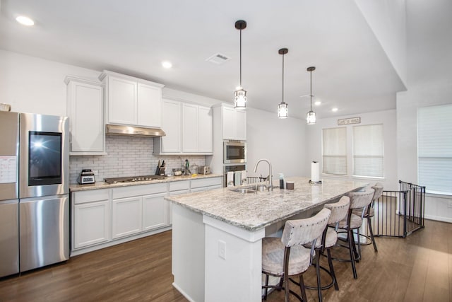 kitchen with white cabinetry, hanging light fixtures, an island with sink, and stainless steel appliances