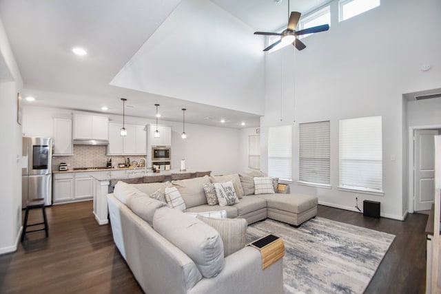 living room featuring ceiling fan, sink, dark hardwood / wood-style floors, and a high ceiling