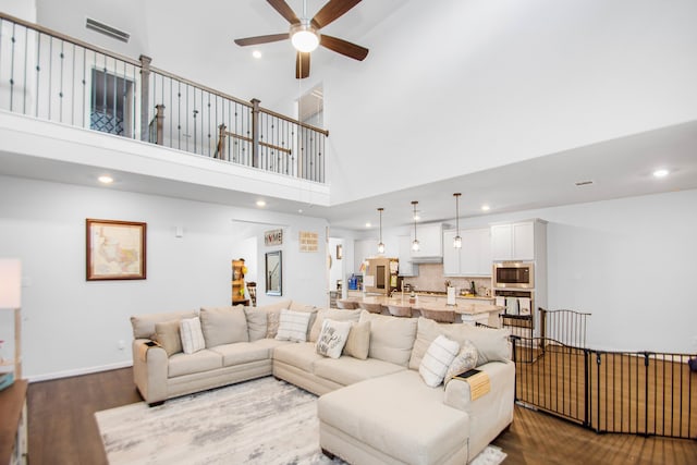 living room with hardwood / wood-style floors, a towering ceiling, and ceiling fan