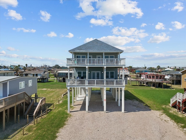 rear view of house featuring a balcony and a yard