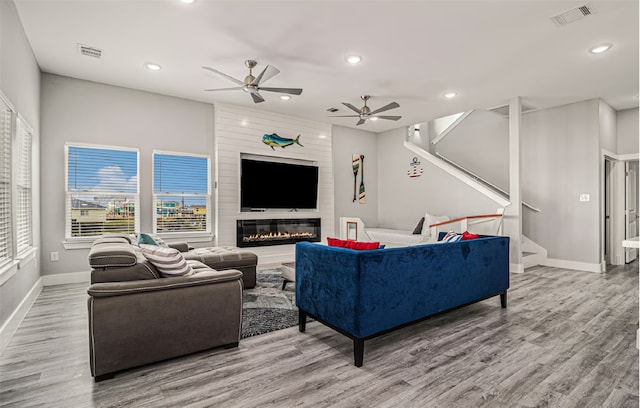 living room with hardwood / wood-style floors, ceiling fan, and a fireplace