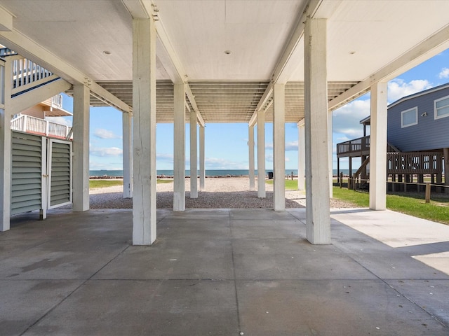 view of patio / terrace with a water view, a carport, and a view of the beach