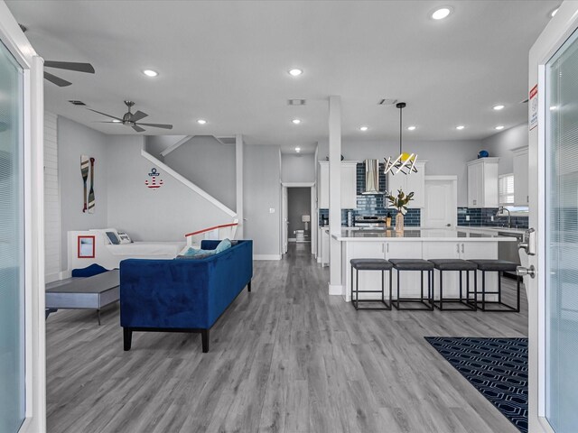 living area with a ceiling fan, light wood-style flooring, and recessed lighting