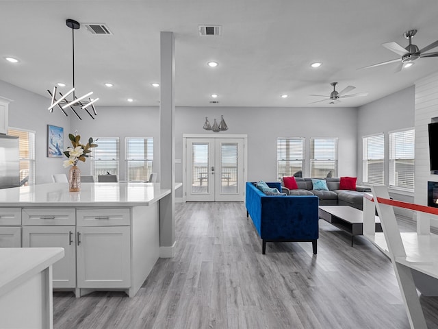 kitchen featuring ceiling fan with notable chandelier, white cabinets, decorative light fixtures, and a healthy amount of sunlight