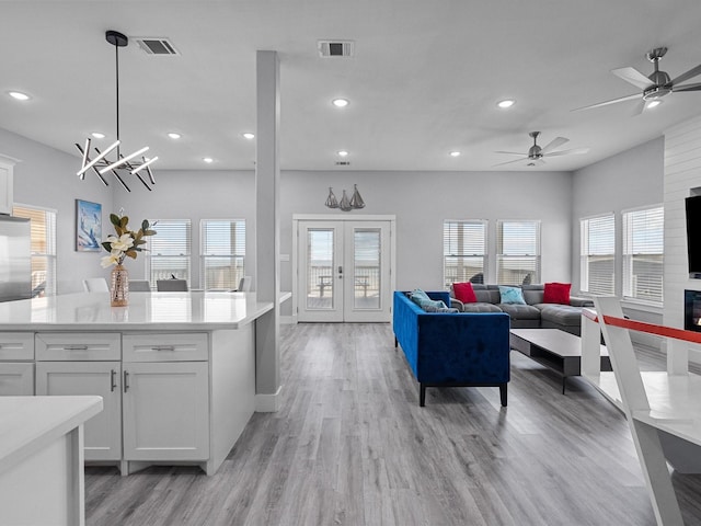 interior space featuring light wood finished floors, white cabinetry, visible vents, and open floor plan