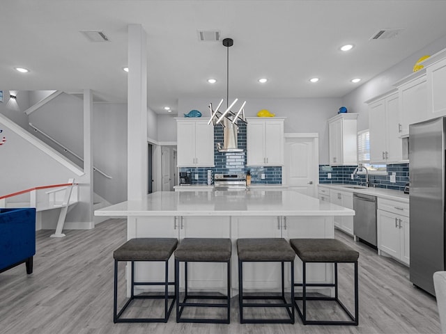 kitchen with appliances with stainless steel finishes, decorative backsplash, a breakfast bar, and a sink
