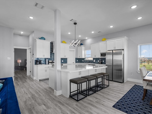 kitchen with a center island, white cabinetry, appliances with stainless steel finishes, and hanging light fixtures