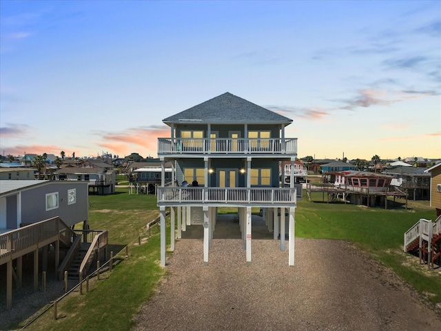 rear view of house featuring stairway, a lawn, a carport, and driveway