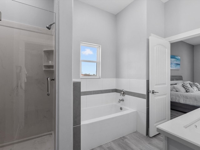 bathroom featuring a stall shower, ensuite bath, a garden tub, and wood finished floors