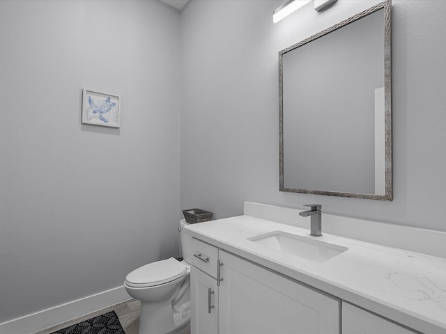 bathroom with vanity, toilet, baseboards, and wood finished floors