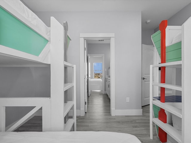 bedroom with baseboards, visible vents, and wood finished floors