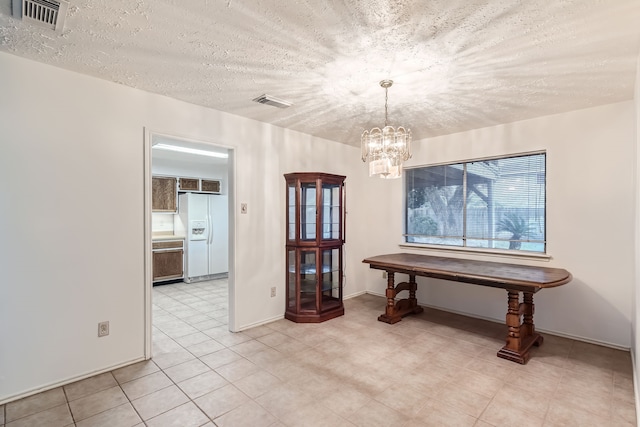 interior space with light tile patterned floors, a textured ceiling, and an inviting chandelier