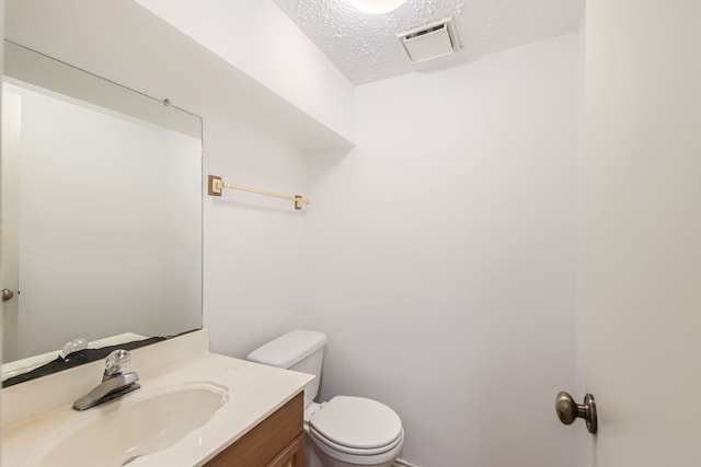 bathroom featuring a textured ceiling, vanity, and toilet