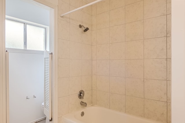 bathroom featuring tiled shower / bath combo and toilet