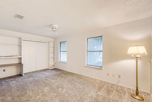 unfurnished bedroom with a closet, a textured ceiling, ceiling fan, and carpet floors