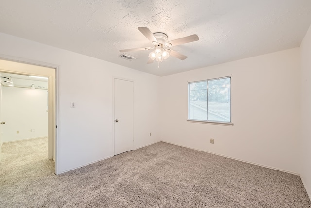 unfurnished bedroom featuring a textured ceiling, carpet flooring, ceiling fan, and a closet