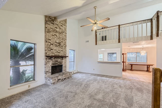 unfurnished living room featuring a fireplace, beamed ceiling, high vaulted ceiling, ceiling fan with notable chandelier, and carpet floors