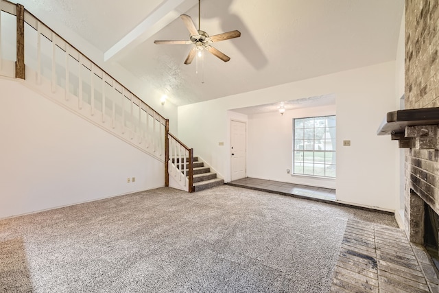 unfurnished living room featuring lofted ceiling with beams, a brick fireplace, carpet flooring, ceiling fan, and a textured ceiling