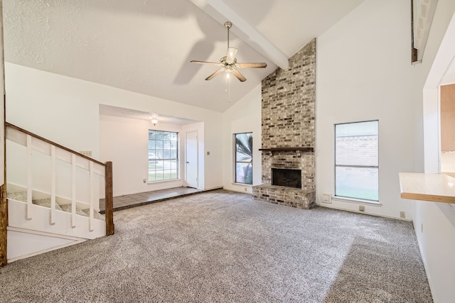 unfurnished living room featuring a fireplace, high vaulted ceiling, carpet flooring, beamed ceiling, and ceiling fan