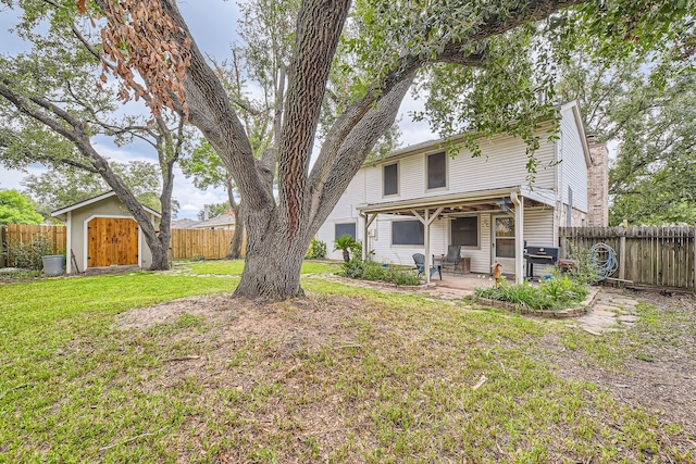 rear view of property with a yard, a storage shed, and a patio area