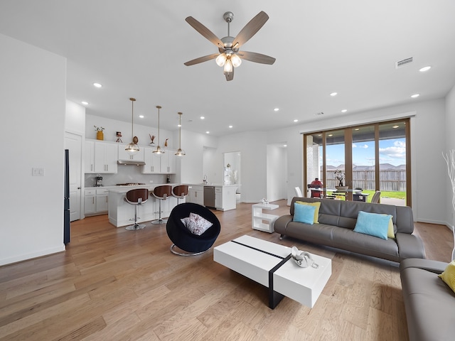 living room featuring ceiling fan and light hardwood / wood-style floors