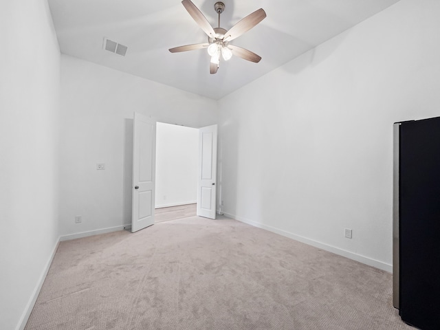 unfurnished bedroom with light colored carpet, ceiling fan, and stainless steel fridge