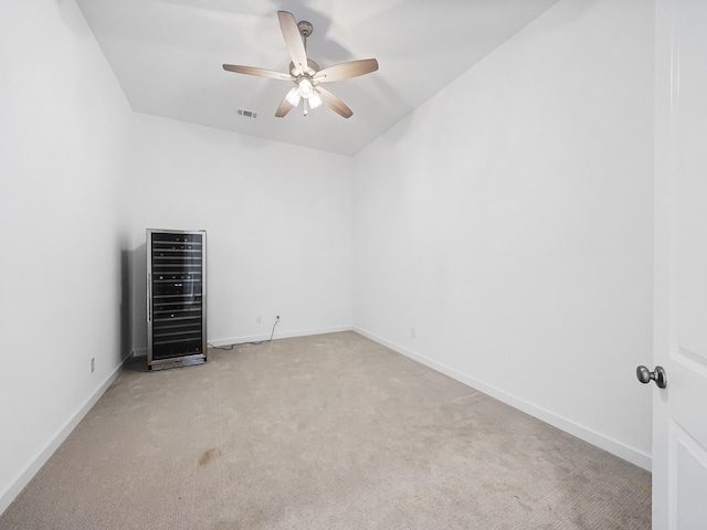 unfurnished room with light colored carpet, ceiling fan, and wine cooler