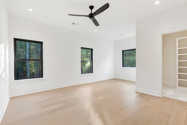 unfurnished bedroom featuring light hardwood / wood-style floors, a spacious closet, and ceiling fan