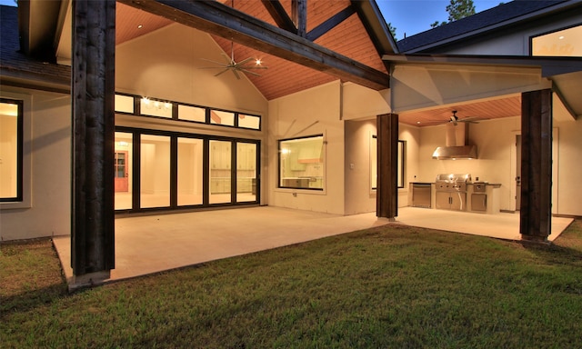 back of property with a patio, ceiling fan, a lawn, and exterior kitchen