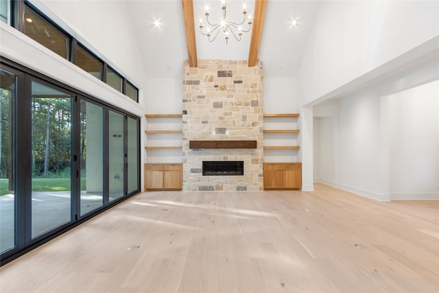 unfurnished living room featuring a chandelier, beam ceiling, high vaulted ceiling, and a stone fireplace