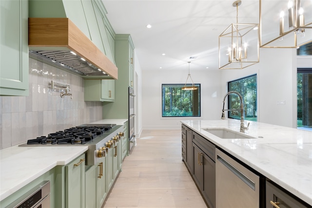 kitchen featuring premium range hood, sink, stainless steel appliances, and decorative light fixtures