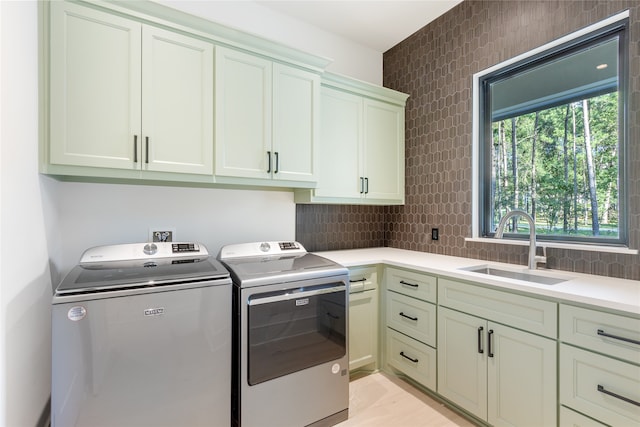 laundry area featuring cabinets, separate washer and dryer, and sink