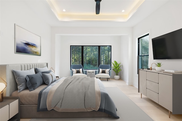 bedroom featuring light hardwood / wood-style floors and a tray ceiling