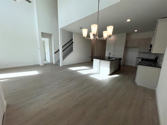 kitchen featuring light hardwood / wood-style floors, a kitchen island with sink, hanging light fixtures, a chandelier, and sink